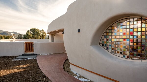 An eye-shaped portal is filled with a metal framework of multicolored iridescent glass tiles by artist Greg Reich that move and shimmer in the wind.