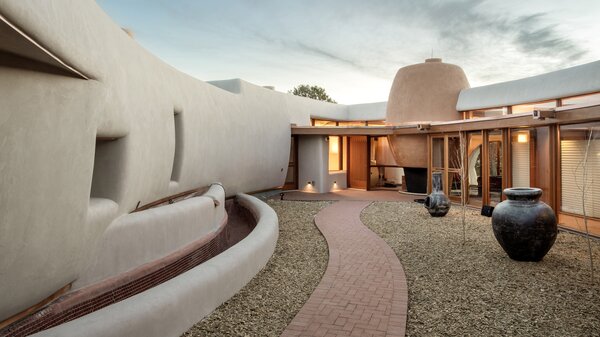 A path leading through the home’s interior courtyard leads to a massive double-sided hearth that serves an outdoor patio and the interior living area. It takes visual cues from traditional American Indian ceramic vessels.