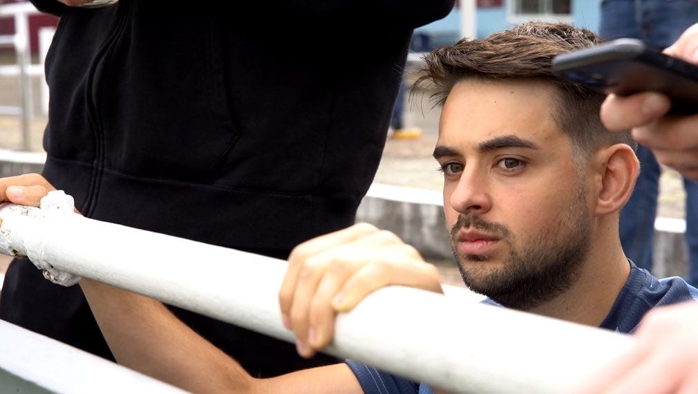 Man sitting in sports stadium stands looking anxiously onto the field