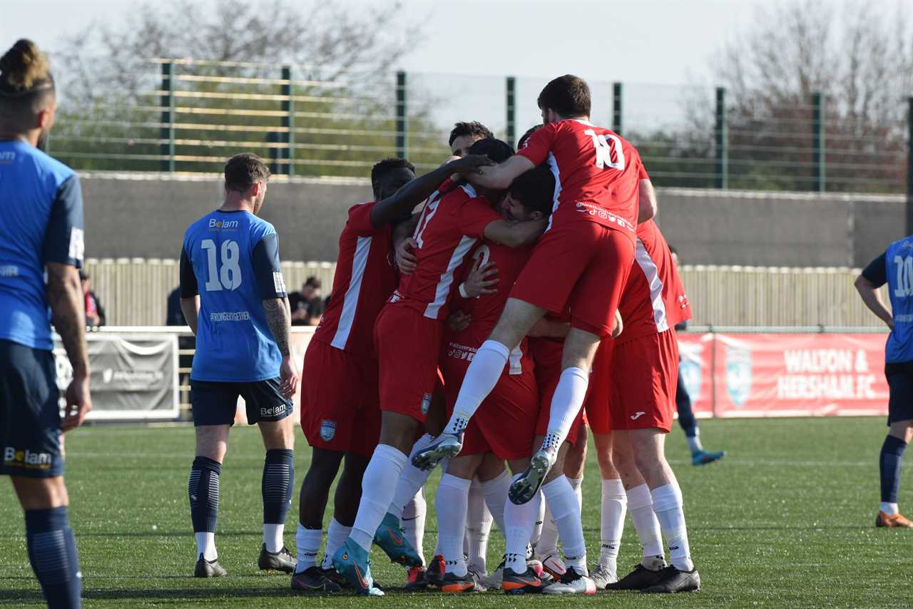 Soccer players jump on top of each other in celebration on the field