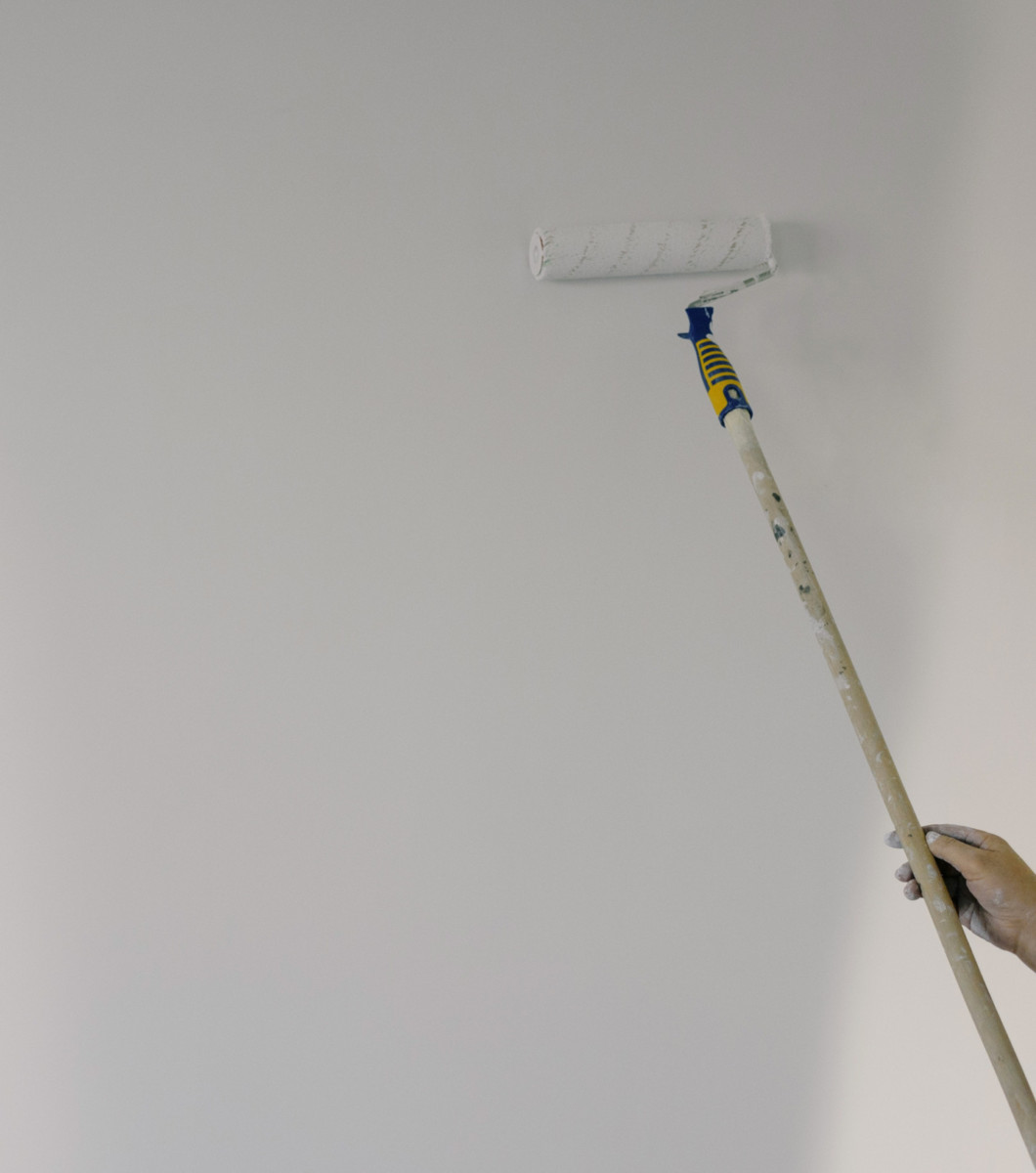 A maintenance man man restoring and repainting a ceiling leak