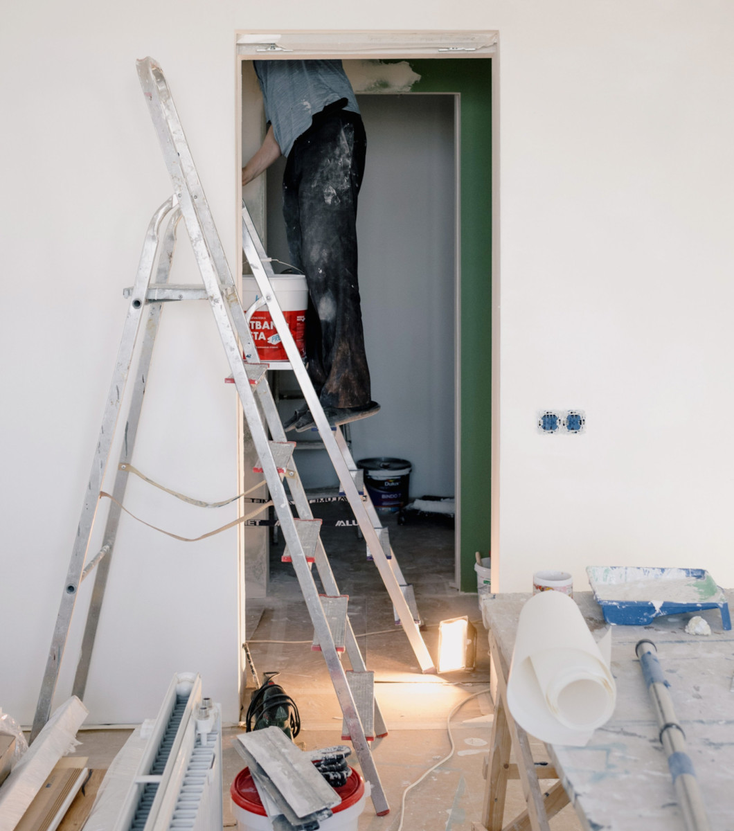 A repair man fixing a clogged pipe in the ceiling that lead to water damage