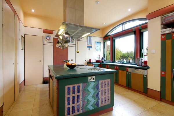 The kitchen is located just steps from the main living areas. A large central island outfitted with custom mosaic telework anchors the space, complementing the colorful cabinetry.