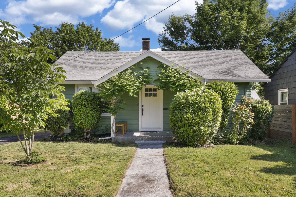 a cottage home with a small front porch and green exterior