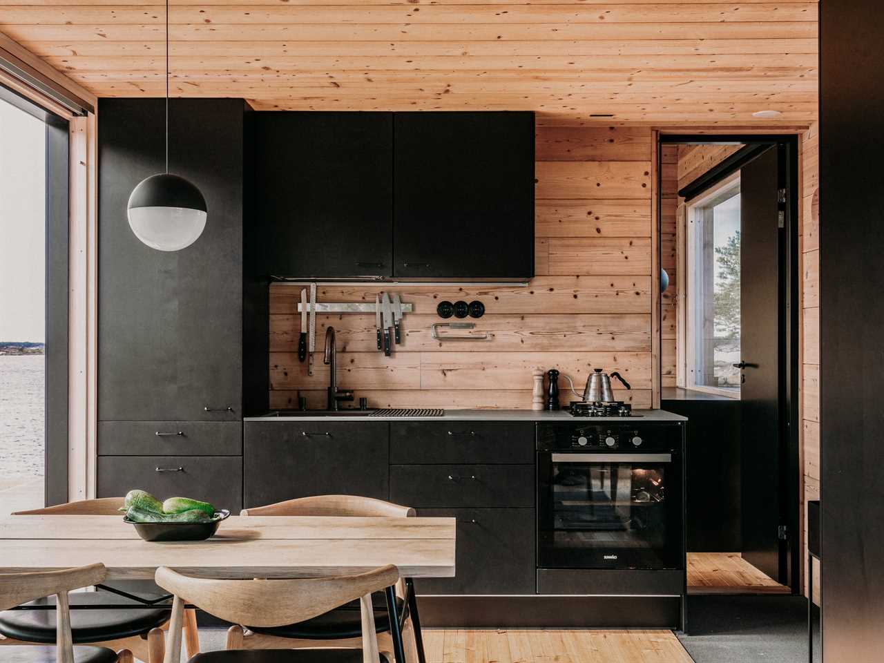 a kitchen with black cupboards and wooden walls