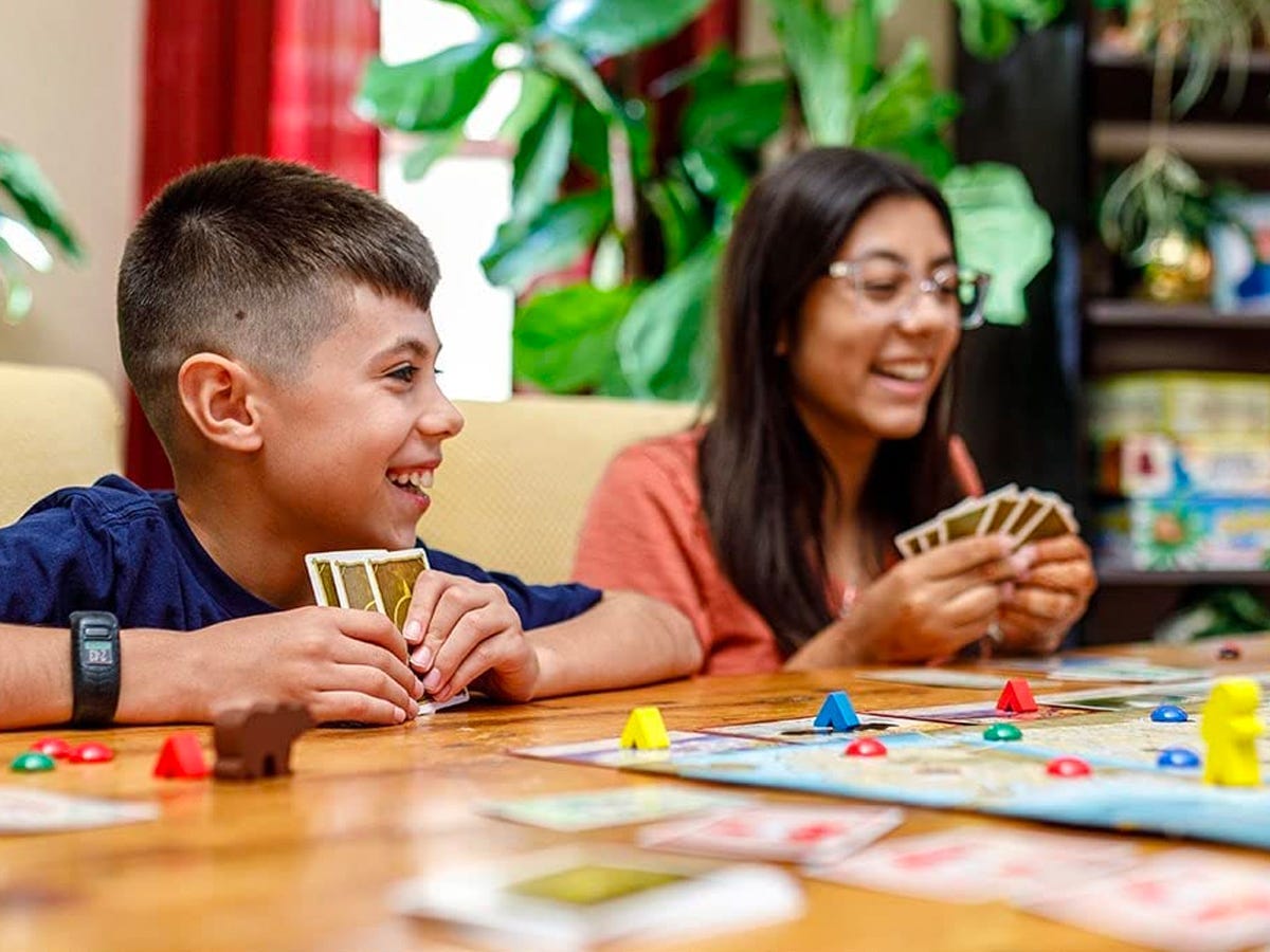 Two kids holding a hand of cards while playing  Trekking The National Parks: The Board Game for National Park Lovers