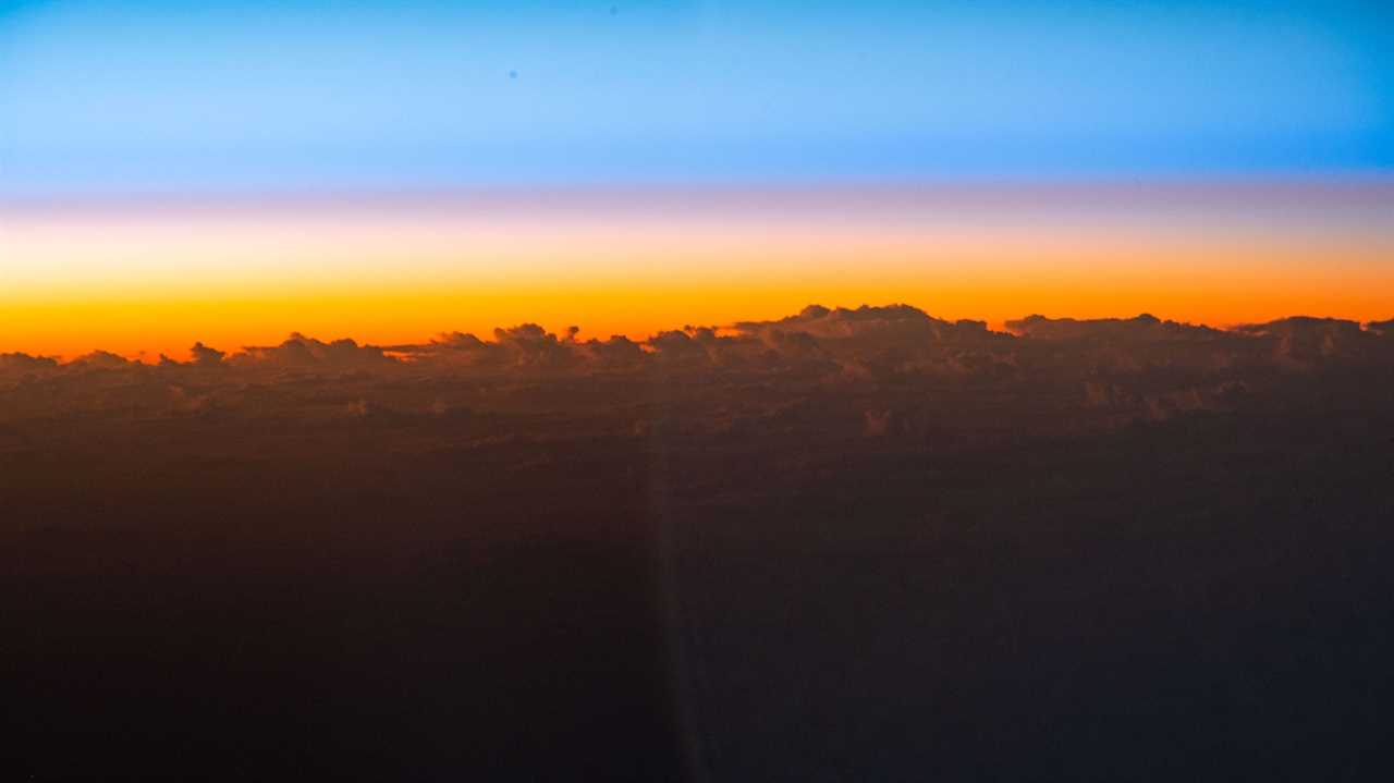 sunrise orange sky peeks above cloud tops