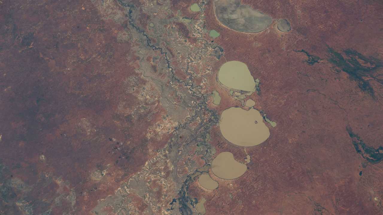 red landscape with muddy brown lakes and thin blue river