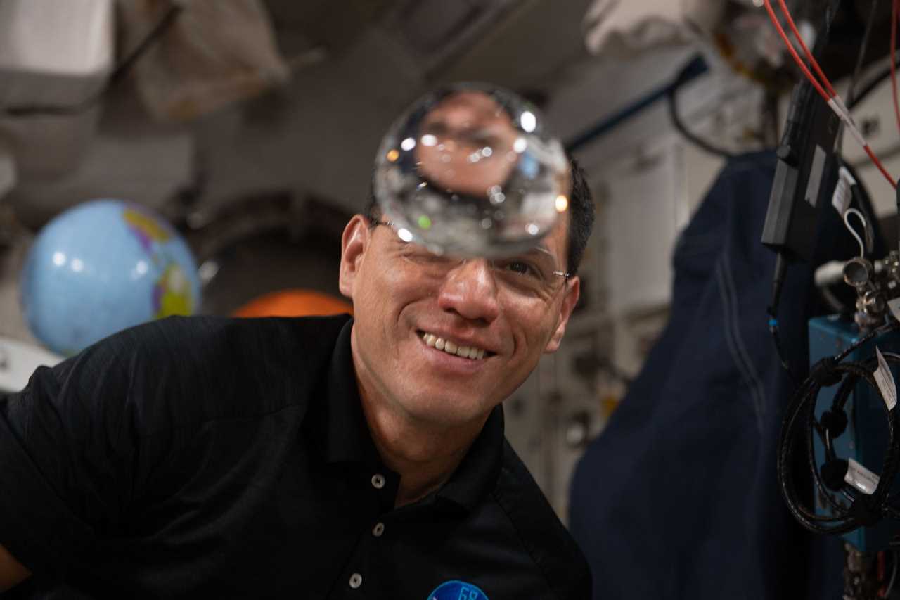 astronaut looks at floating bubble of water on international space station