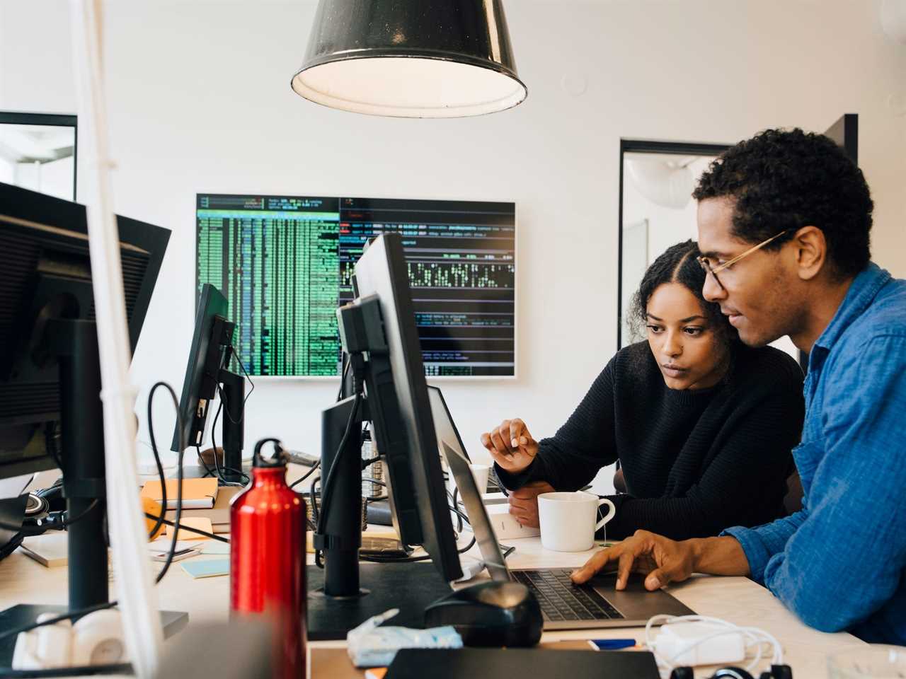 Engineers coding over laptop on a desk in an office