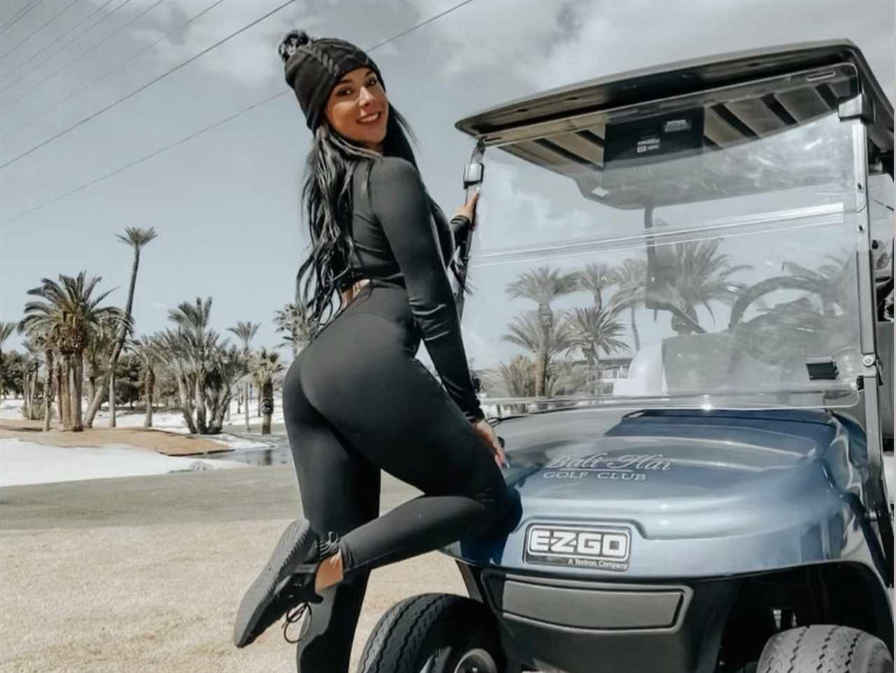 woman stands with a golf cart