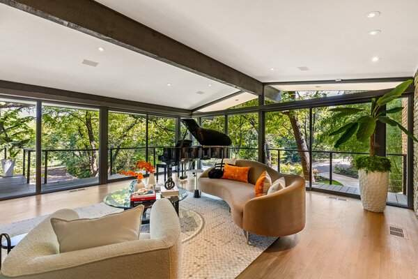 Floor-to-ceiling glazing wraps around the main living area, providing direct outdoor access.