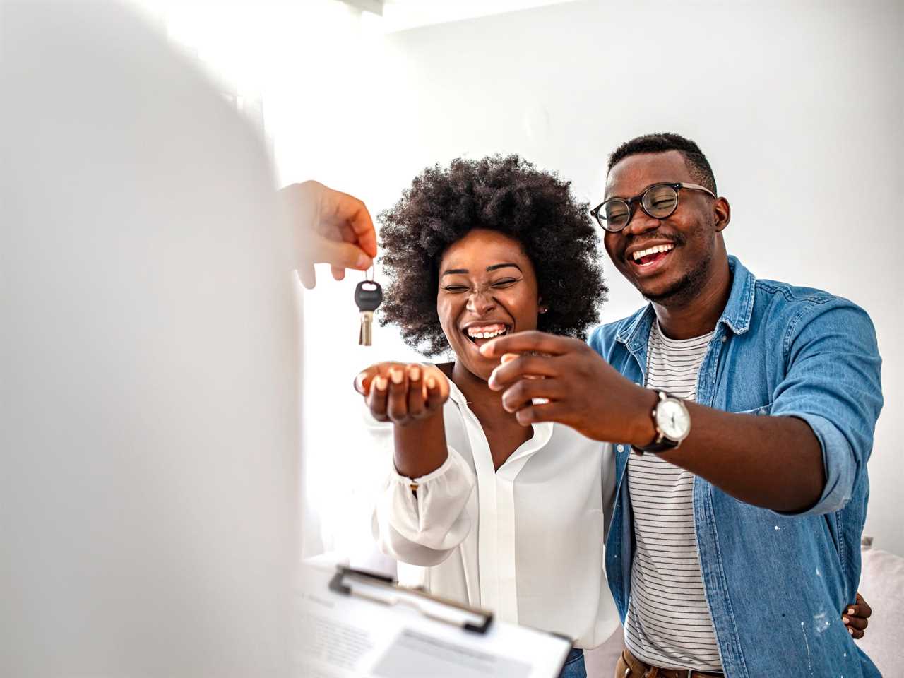 couple smiles and laughs as they are handed the key to their new house.