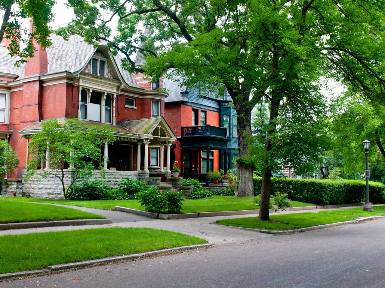 Red Victorian-style houses on a tree-lined residential street