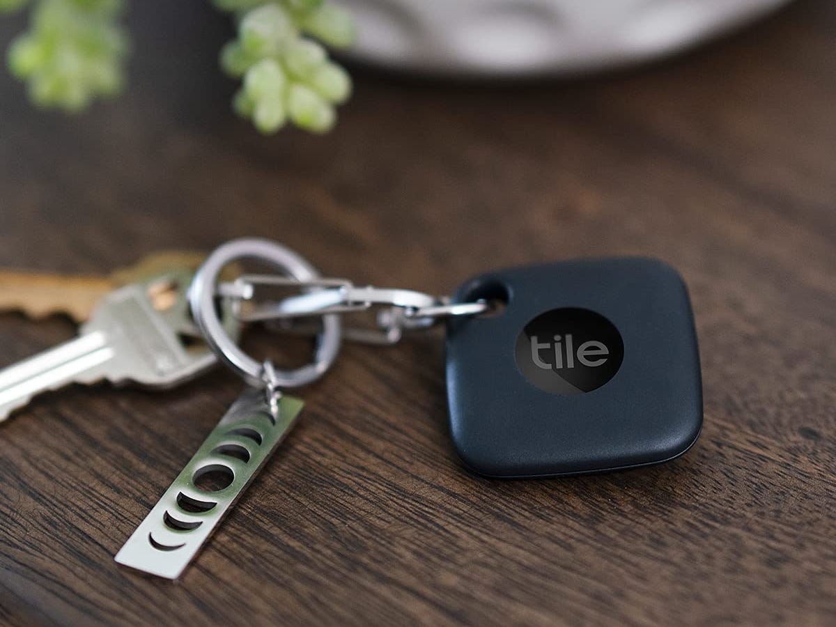 A set of keys on a wooden table with the Tile Mate attached to a keychain.