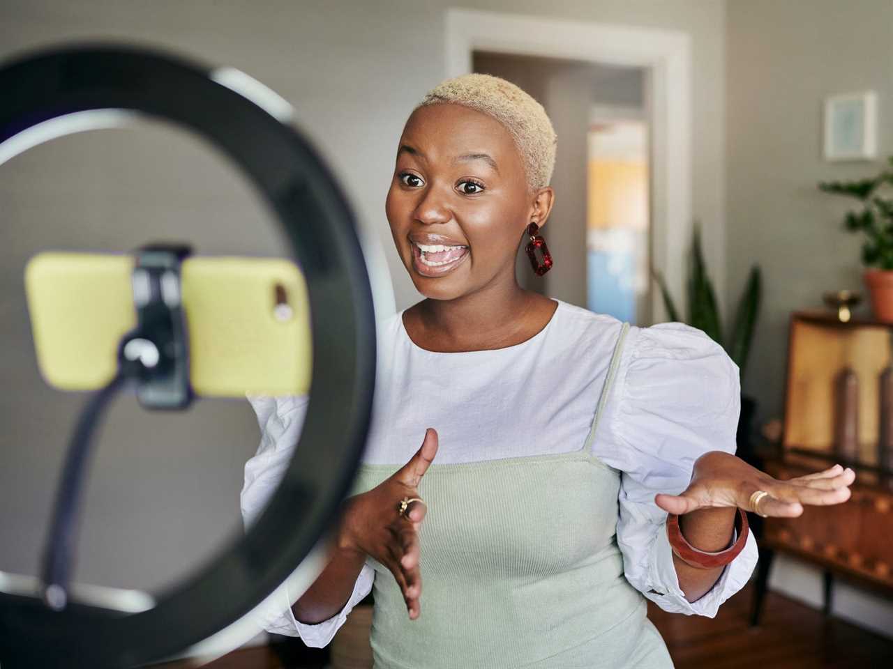 Smiling young African female influencer doing a vlog post at home