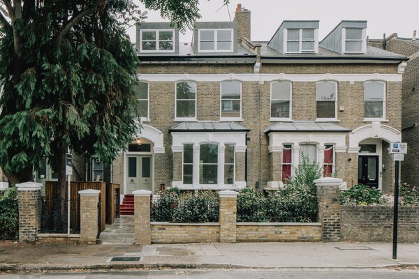 Dressed in sandstone-colored brick and white stucco, the historic residence sits behind a black-iron gate and features a landscaped front garden leading up to its arched entryway.