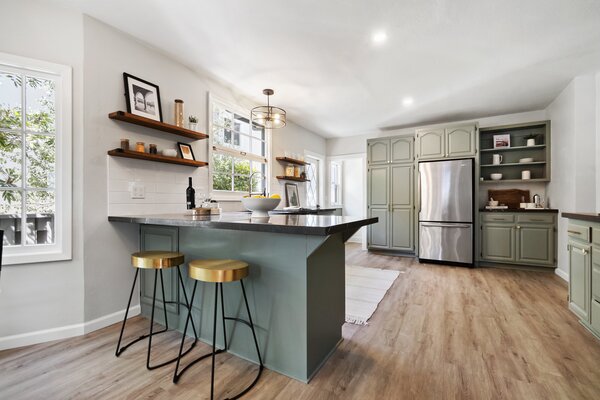 Green hues continue into the kitchen, a light-filled space fitted with all new appliances and custom cabinetry. An L-shaped worktop ensures ample room for meal prepping.