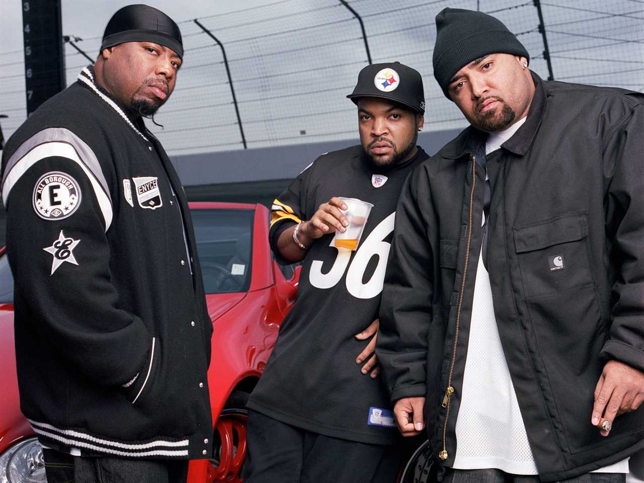 Three members of hip-hop group Westside Connection lean against cars wearing Carhartt clothing