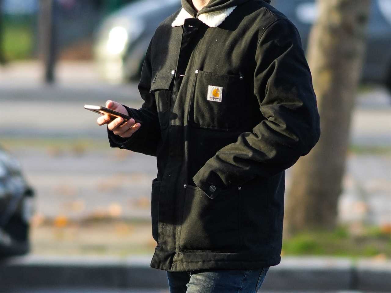 A passerby wears a coat form Carhartt outside a fashion show