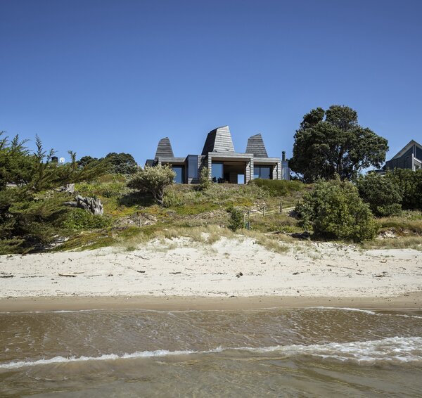 "‘With our designs we like embedding a narrative, another level of engagement,’ explains architect Ken Crosson, whose designs often evince a playful or subversive element. It was local gold-mining history that lent its narrative to Light Mine House, a beach bach at Kūaotunu, on the east coast of the Coromandel Peninsula. Nestling among the sand dunes and pīngao, a series of boxes is made unique by the addition of tapering skylights that reach for the sky."