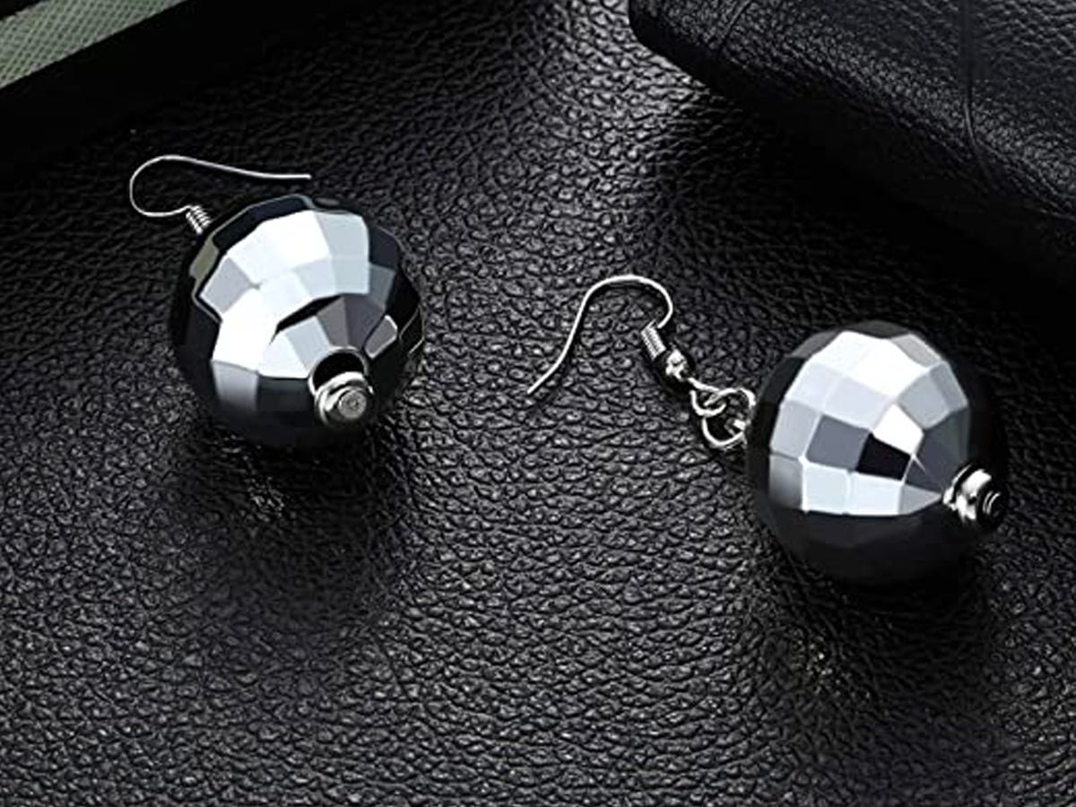 Pair of disco ball earrings on a black leather surface