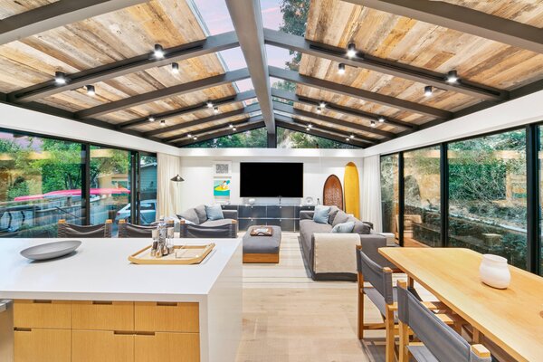 Vaulted wood-beamed ceilings cap the main living areas, which are encompassed by sliding glass doors that open to the wraparound Ipe-wood deck.