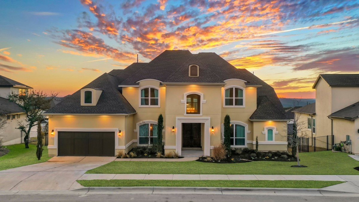 french country home with yellow painted stucco siding