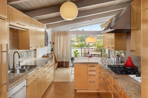 The kitchen is well equipped with all new appliances and custom cabinetry. Sliding glass doors provide direct access to the partially covered patio that wraps around to the back.