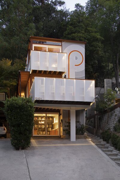 The three-story residence sits nestled into a hillside, enhancing its sense of privacy. The second-level deck creates a covered outdoor area for the office space on the ground floor.