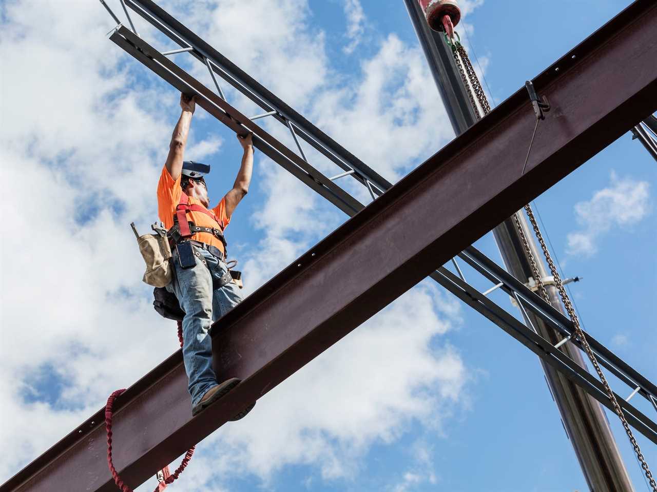 Ironworker at construction site installing roof joist