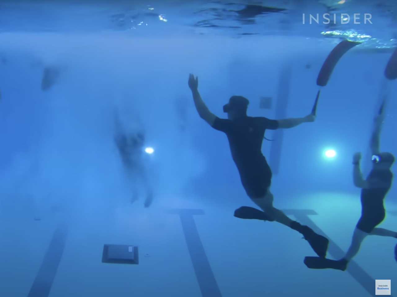 Navy recruits swim inside a pool during basic training.