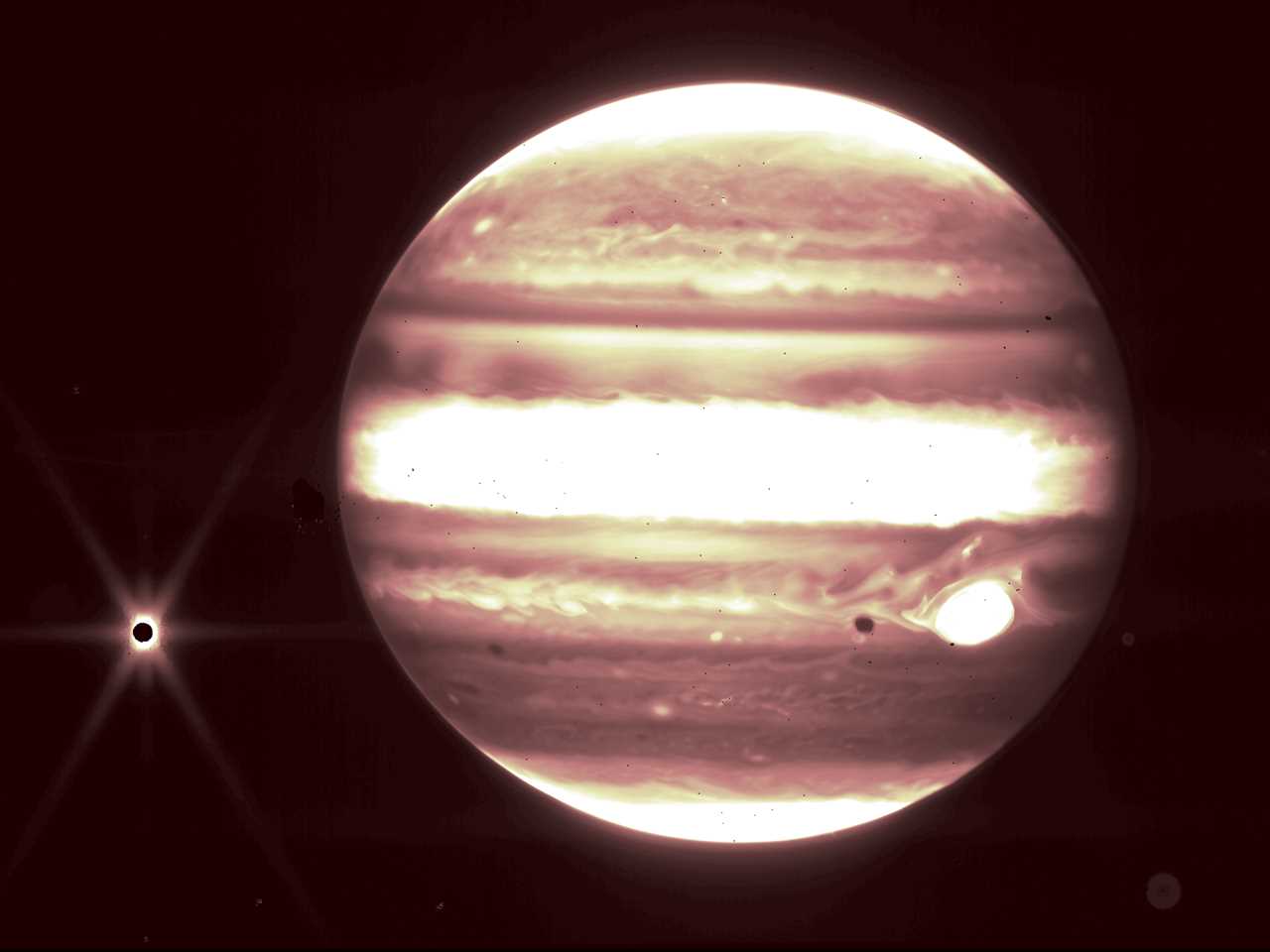 jupiter in white and orange infrared with dark moon europa surrounded by yellow light