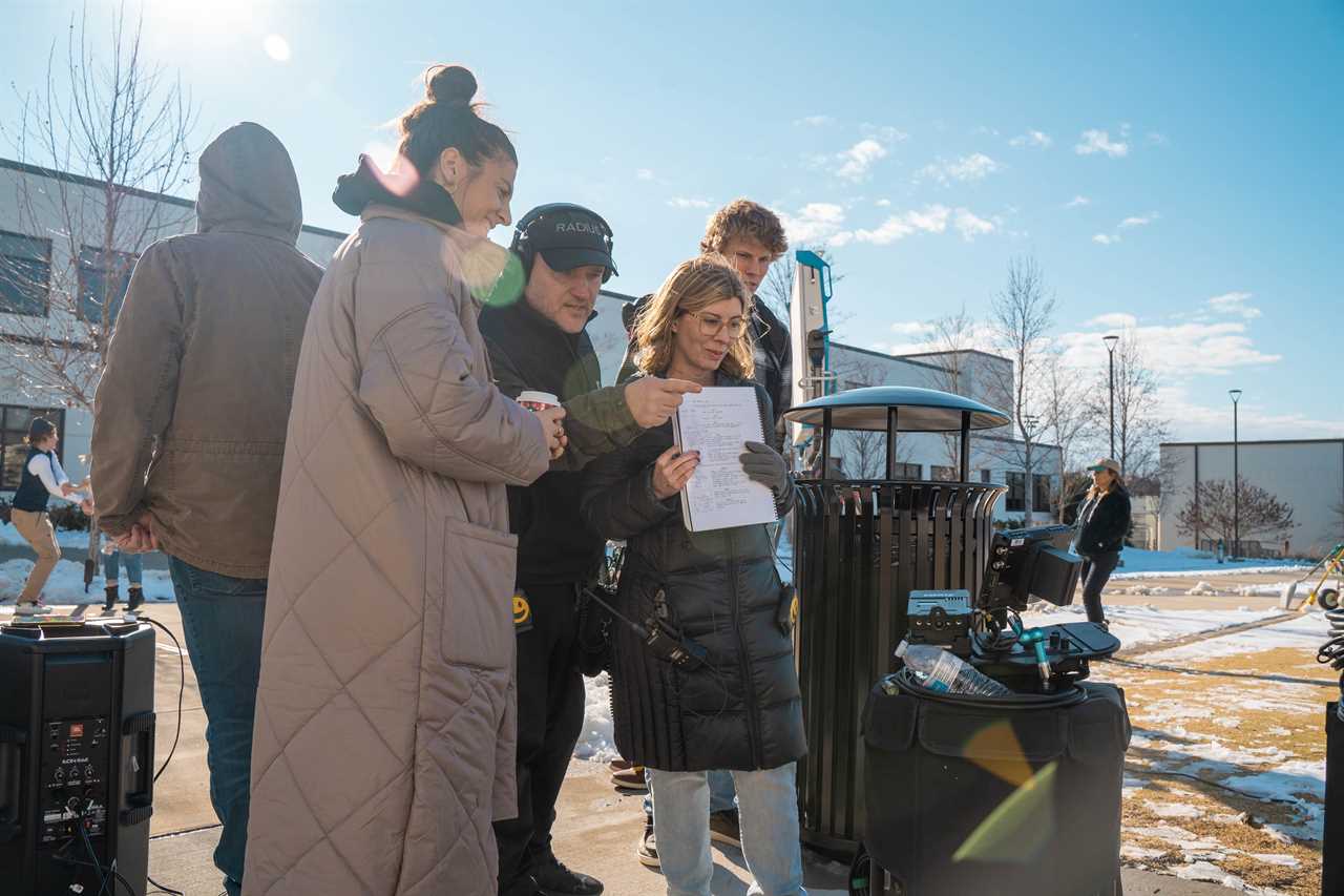 A group of people standing looking at what a movie camera is capturing on a film set