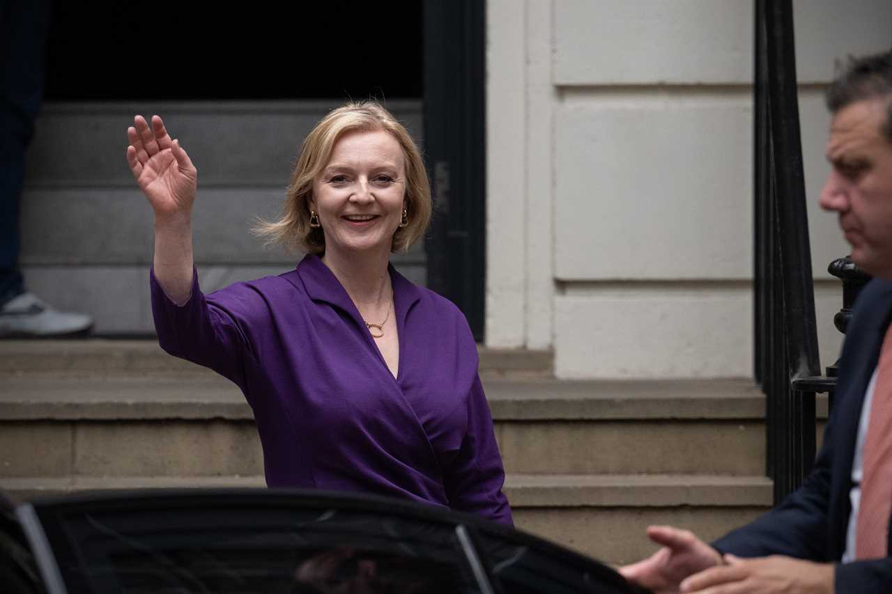 A woman waves as she exits a building.