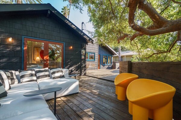 An expansive deck, shaded by surrounding trees, offers a relaxing welcome upon arrival.