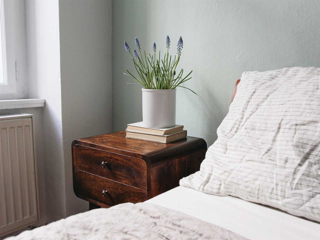 Vintage side table next to a bed with white sheets