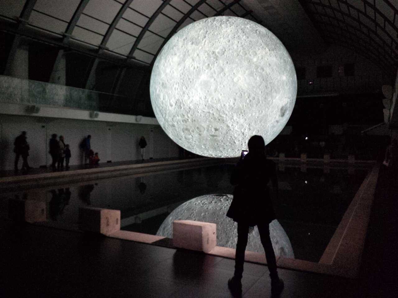 A moon and its reflection over a still pool 