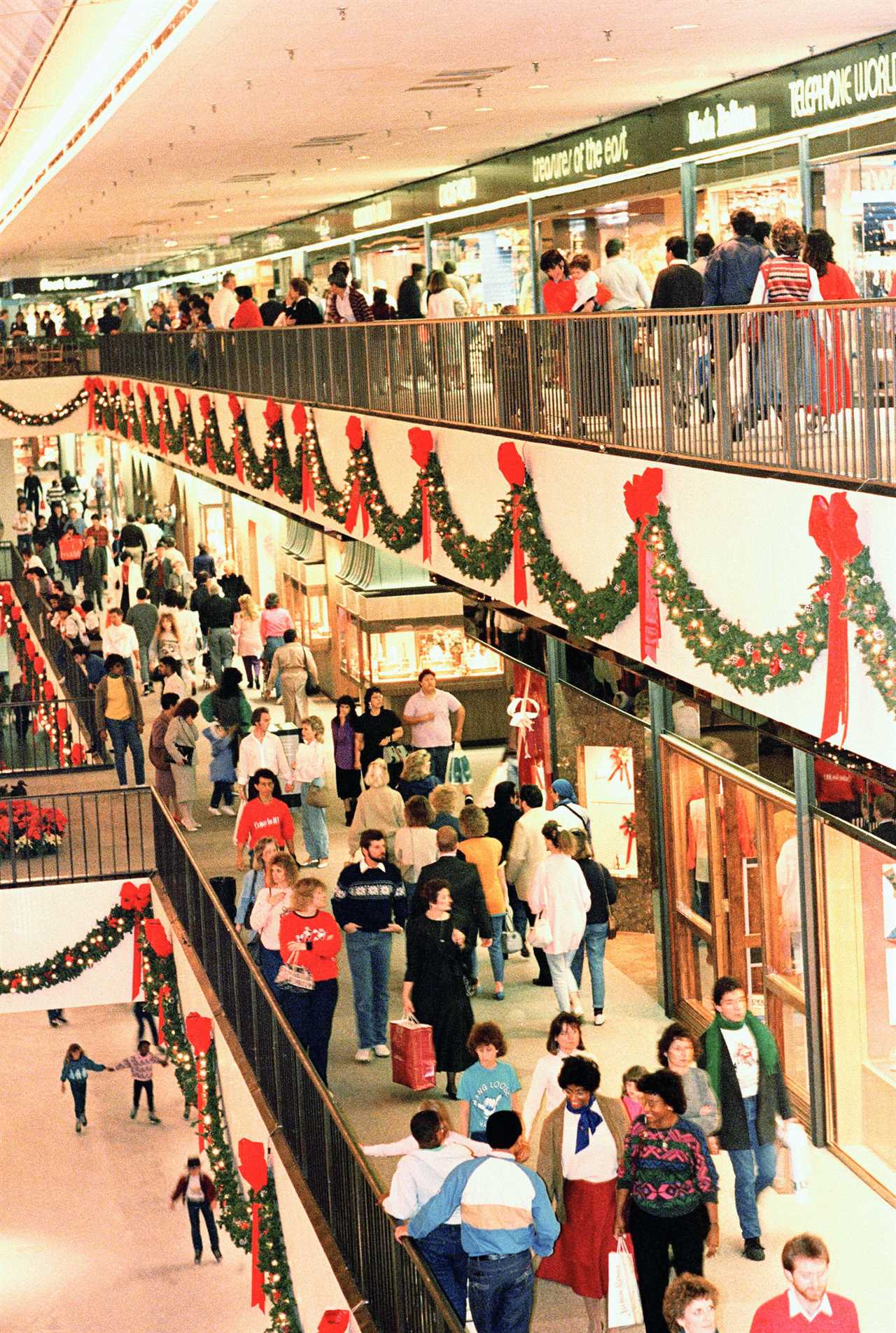 Shoppers walk on upper and lower levels of shopping mall decorated for Christmas