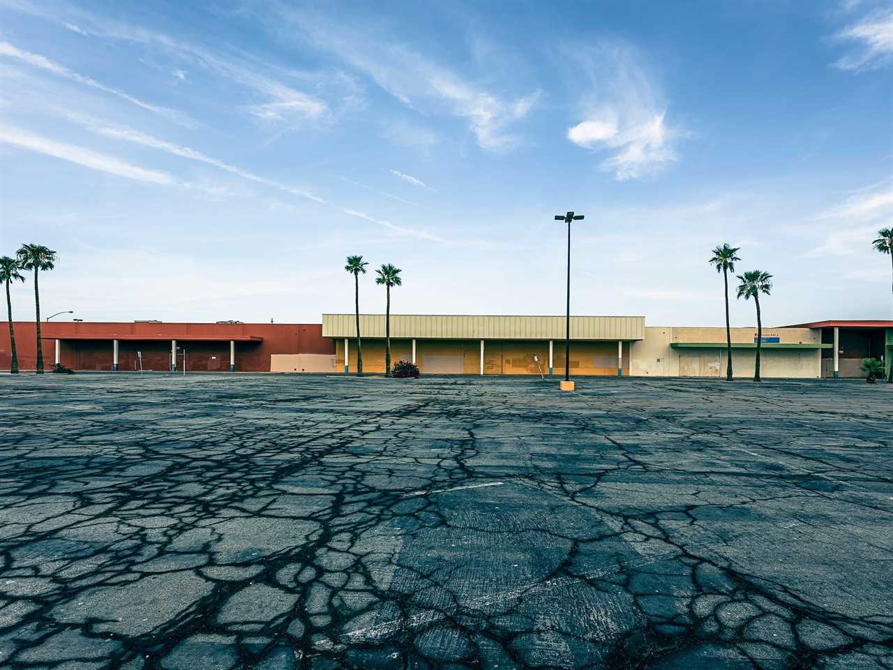 Cracked parking lot in front of vacant shopping center