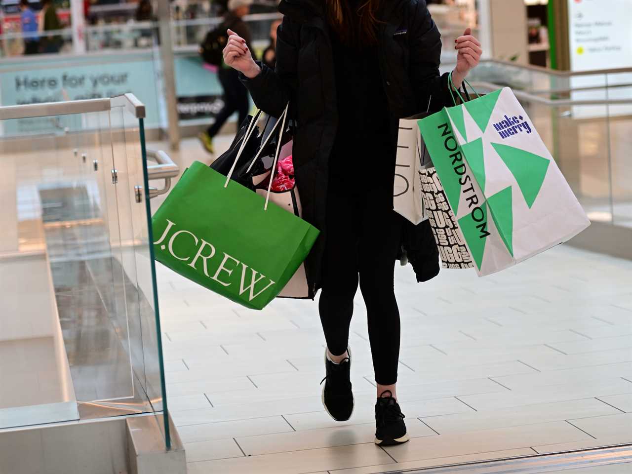 Woman carries armloads of shopping bags while walking through mall