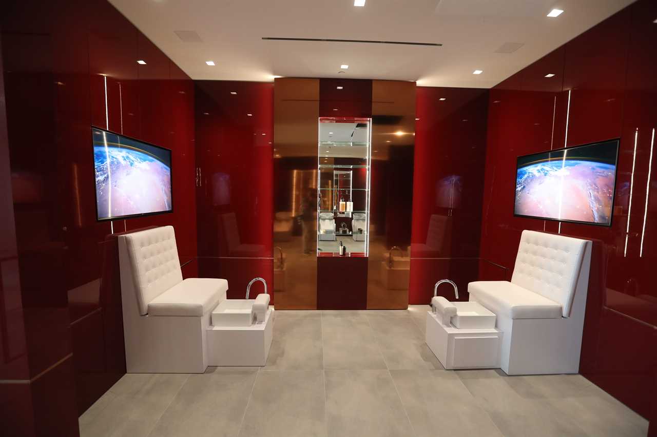 a red beauty salon room with two white chairs and TVs at mansion The One Bel Air