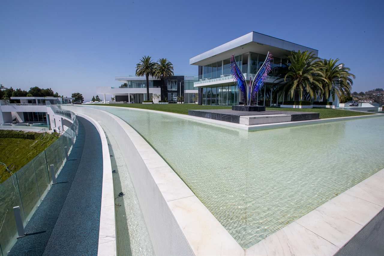 a white building with a blue sculpture of wings and a swimming pool in front of it at mansion The One Bel Air