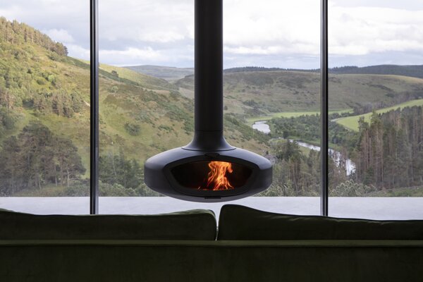 A Firemaker stove is suspended from the ceiling in the open plan living space, to be enjoyed alongside the expansive views from the client’s vintage Ercol chairs and plush green sofa.