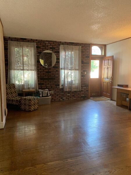 Before: Marina Barnes and Thomas Pittlik bought an 1890 rowhouse in Philadelphia, Pennsylvania in 2019. The living room was at the front of the house, overlooking the sidewalk. The original wood floors were in place, but the front wall was covered in fake brick and the ceiling had popcorn texture.