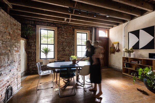 The couple located the dining room to the front of the house, stripping away the excess finishes to reveal the brick and wood structure, as well as the plaster walls. 