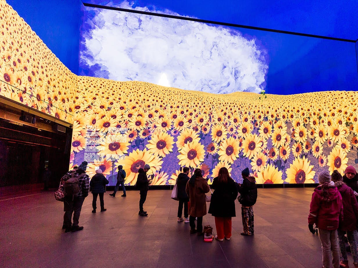 Spectators at a Hilma af Klint exhibition look at surrounding images of sunflowers