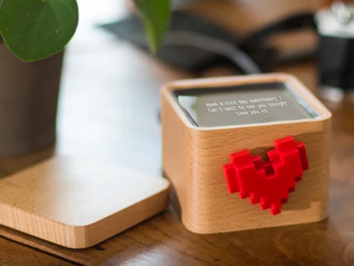 a Lovebox with a red pixelated heart that spins when a long-distance partner sends a message set on a wooden table.