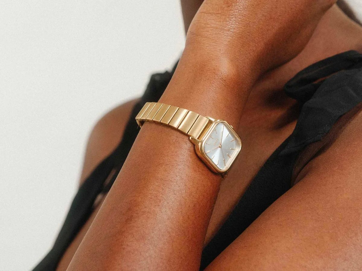 Person holding their hand against their chin while wearing the Esther Square Metal Watch in gold.