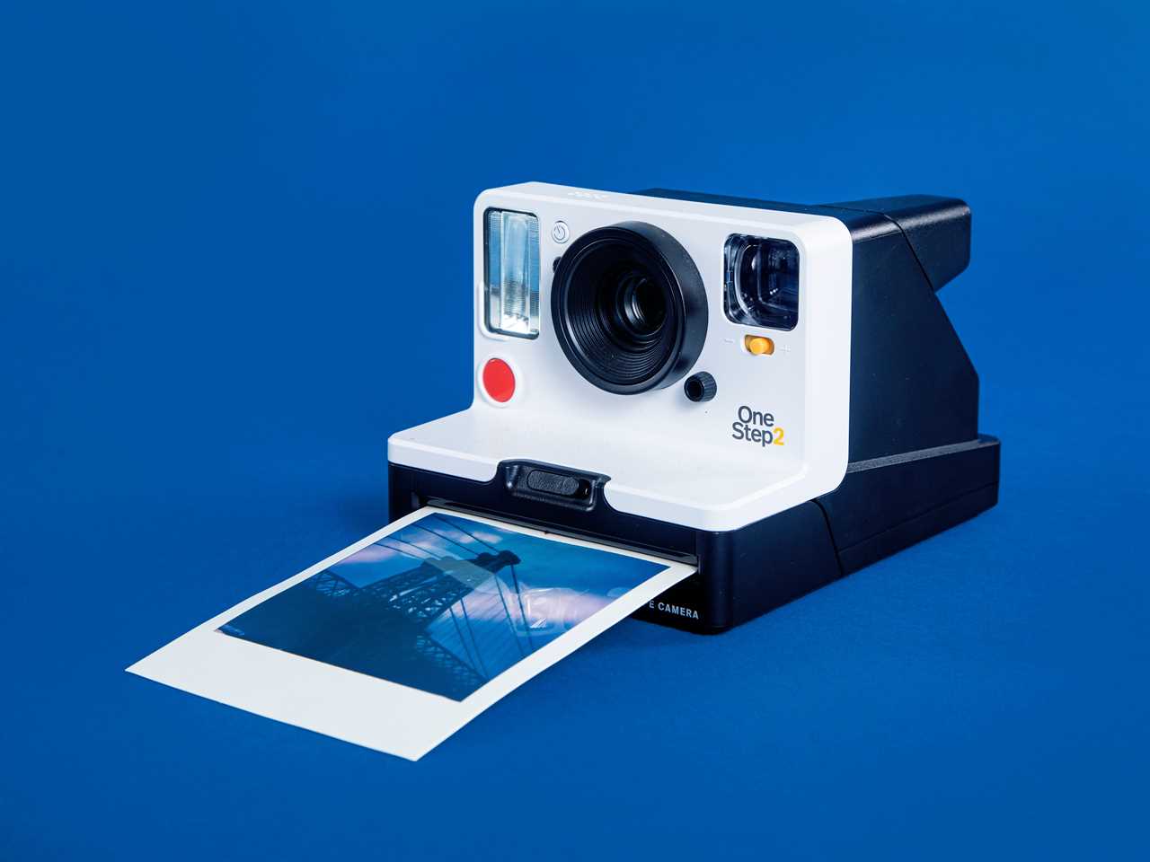 A Polaroid one-step camera developing a photo of a bridge